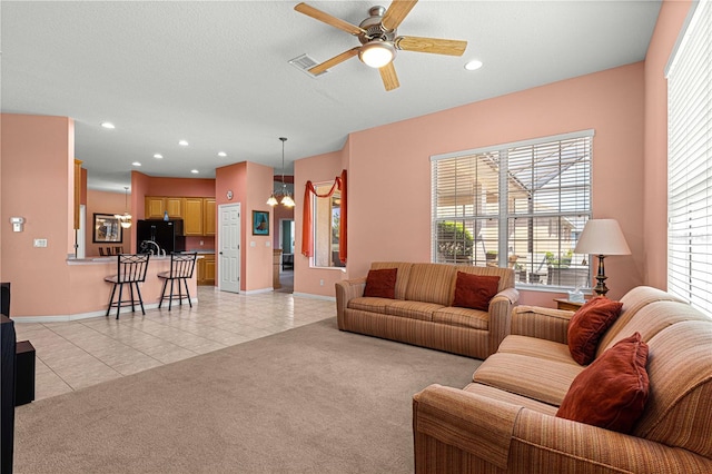 living room featuring a wealth of natural light, light carpet, a textured ceiling, and ceiling fan with notable chandelier