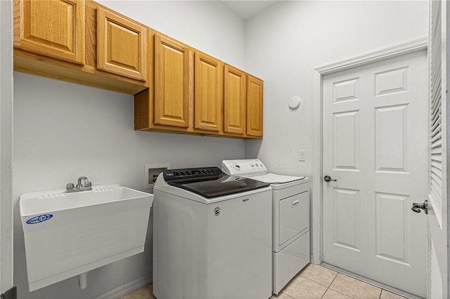 laundry room featuring cabinets, light tile patterned flooring, sink, and washing machine and clothes dryer