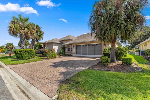 view of front of home featuring a front yard, central AC unit, and a garage