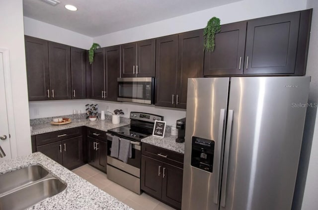 kitchen with appliances with stainless steel finishes, sink, dark brown cabinets, and light stone counters