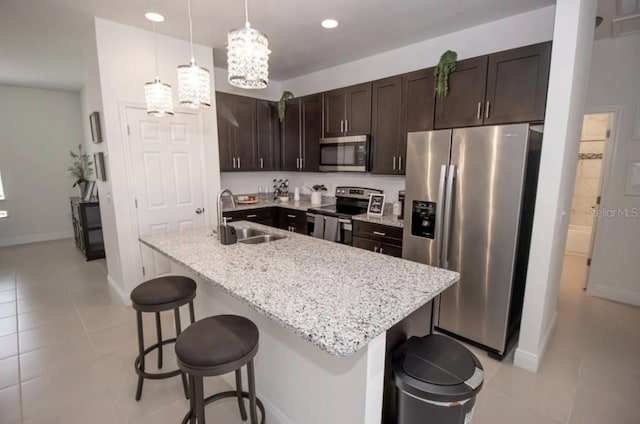 kitchen with a kitchen island with sink, a kitchen bar, sink, pendant lighting, and stainless steel appliances