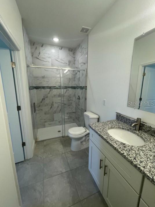 bathroom with toilet, walk in shower, and vanity