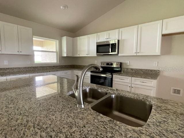 kitchen with white cabinetry, stainless steel appliances, vaulted ceiling, and sink