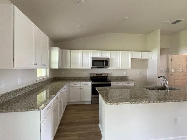 kitchen featuring stone countertops, stainless steel appliances, sink, vaulted ceiling, and white cabinets