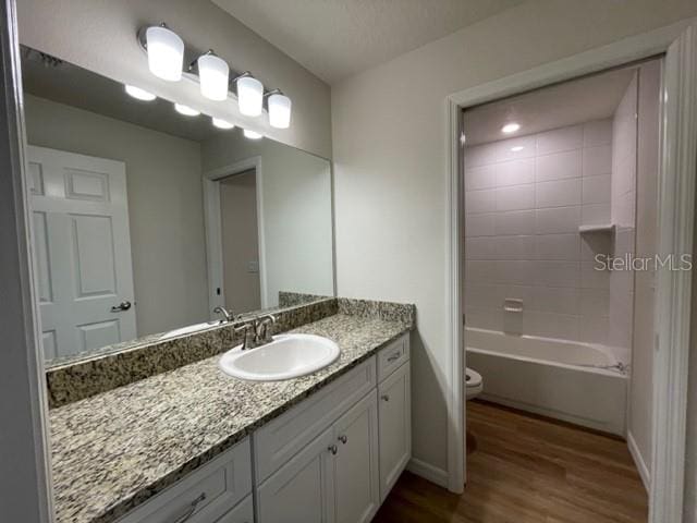 full bathroom featuring toilet, bathtub / shower combination, hardwood / wood-style flooring, and vanity