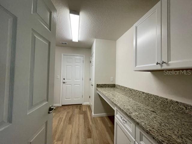 interior space featuring a textured ceiling and light hardwood / wood-style floors