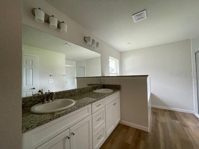 bathroom with vanity, hardwood / wood-style floors, and a shower with door