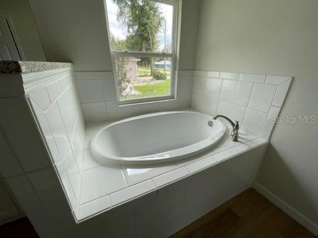 bathroom featuring a wealth of natural light and tiled tub