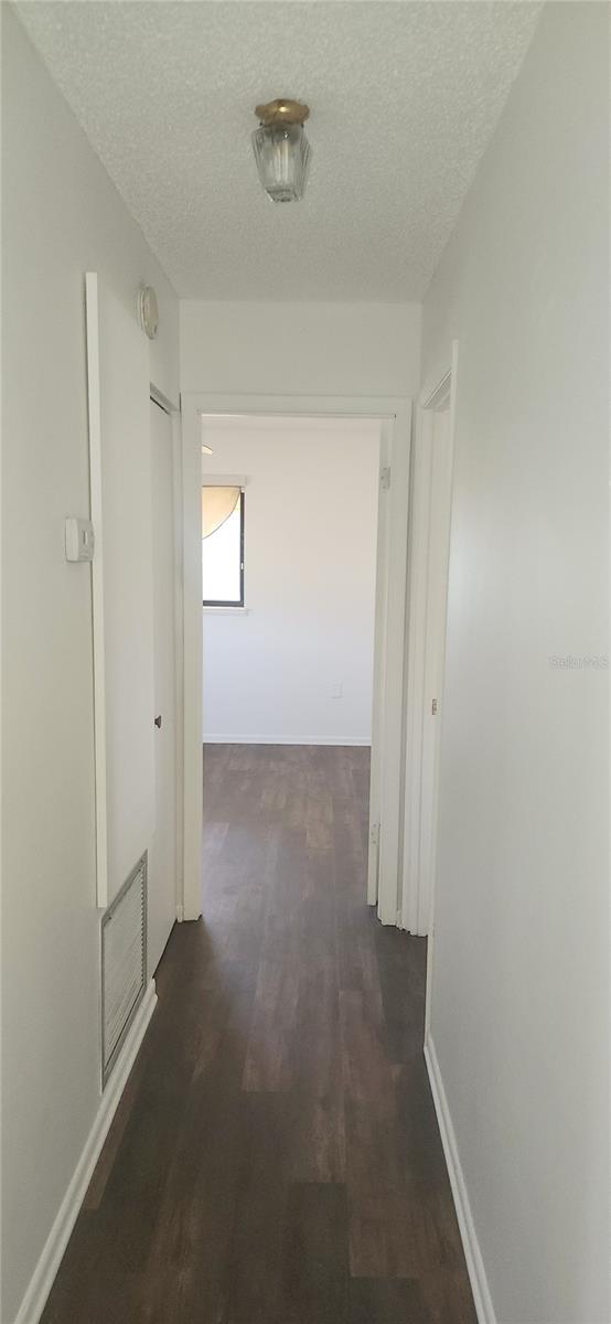 corridor with a textured ceiling and dark hardwood / wood-style floors