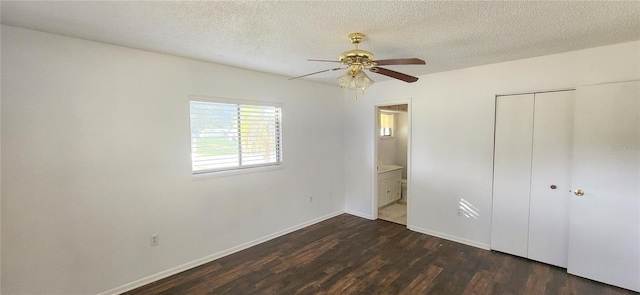 unfurnished bedroom with dark hardwood / wood-style flooring, a textured ceiling, ceiling fan, connected bathroom, and a closet