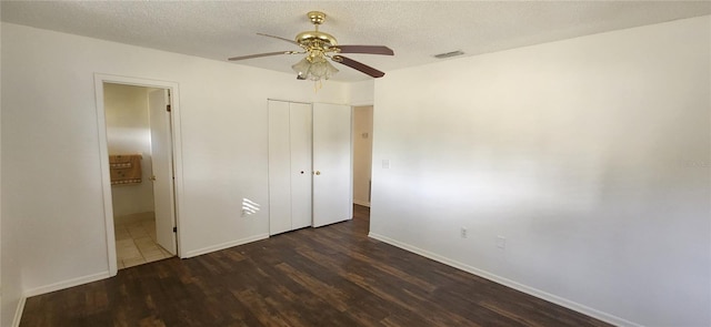 unfurnished bedroom featuring ceiling fan, a closet, dark wood-type flooring, and a textured ceiling