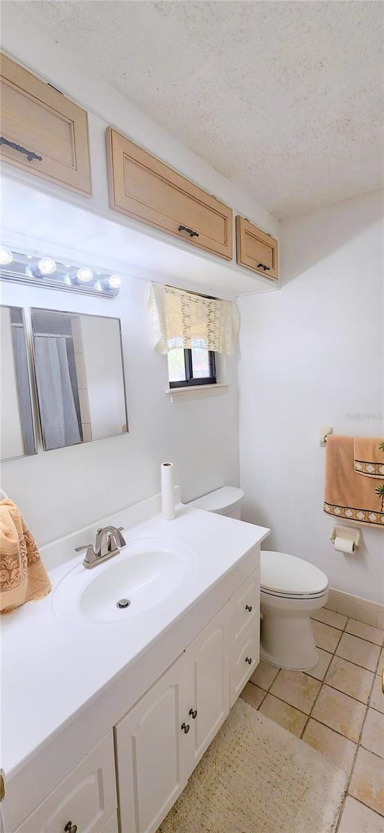 bathroom featuring tile patterned flooring, a textured ceiling, vanity, and toilet