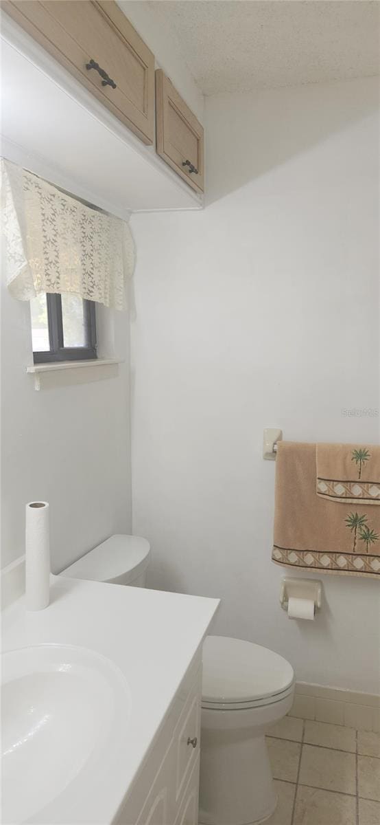 bathroom featuring tile patterned floors, vanity, a textured ceiling, and toilet