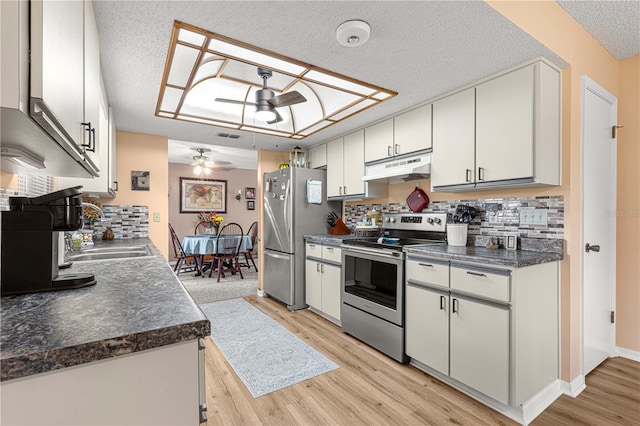 kitchen with stainless steel appliances, sink, white cabinets, light hardwood / wood-style floors, and ceiling fan