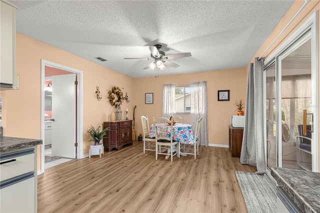 dining room with light hardwood / wood-style floors, a textured ceiling, and ceiling fan