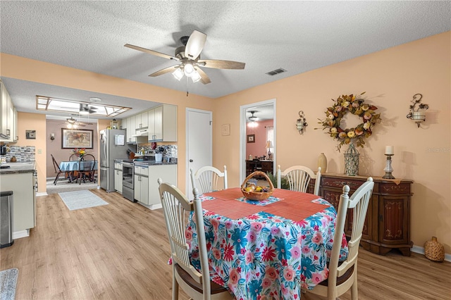 dining space featuring a textured ceiling, light wood-type flooring, and ceiling fan