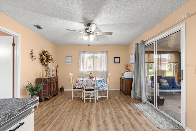 dining room with a textured ceiling, light wood-type flooring, and ceiling fan