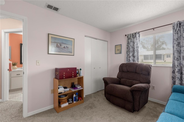 living area with a textured ceiling and light colored carpet