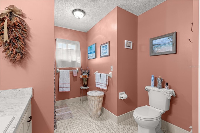 bathroom featuring toilet, a textured ceiling, vanity, and tile patterned floors