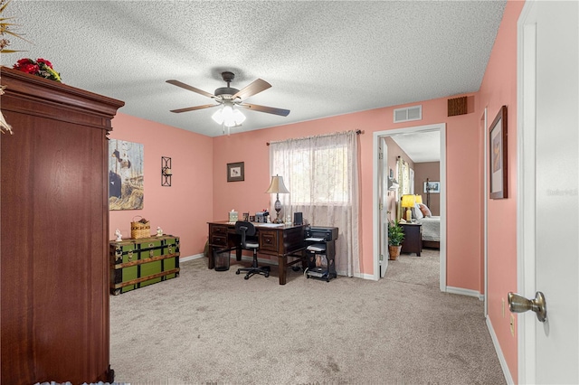 carpeted home office featuring a textured ceiling and ceiling fan