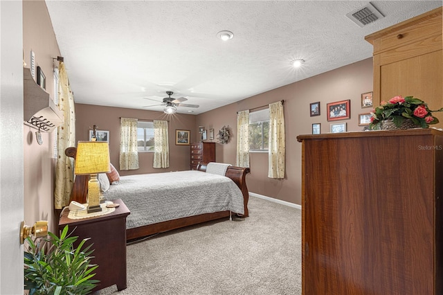 carpeted bedroom featuring ceiling fan and a textured ceiling