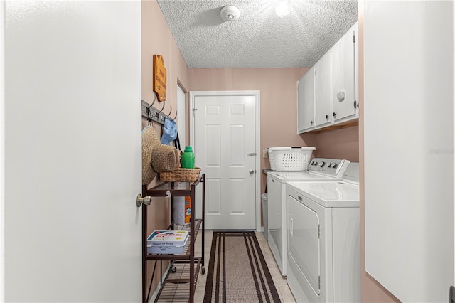 clothes washing area with cabinets, a textured ceiling, washing machine and clothes dryer, and tile patterned flooring