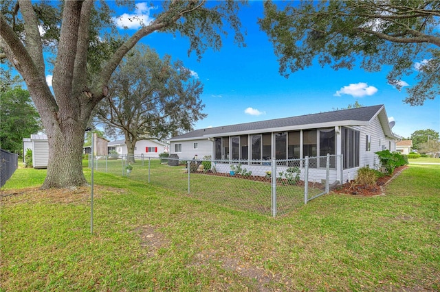 rear view of house featuring an outbuilding, a yard, and a sunroom