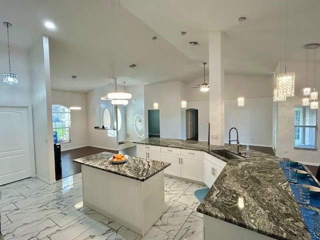 kitchen with ceiling fan, sink, white cabinetry, hanging light fixtures, and a large island