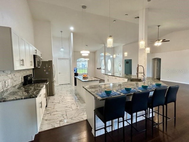 kitchen featuring pendant lighting, black electric range oven, a large island with sink, ceiling fan, and white cabinetry