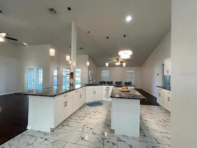 kitchen featuring dark stone counters, white cabinets, hanging light fixtures, sink, and kitchen peninsula