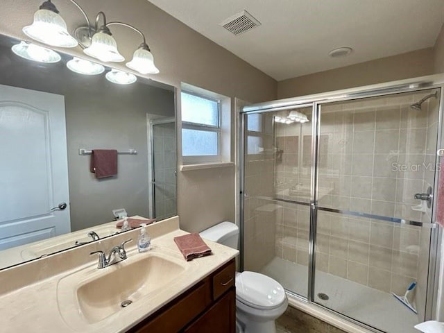 bathroom with a shower with door, vanity, and toilet