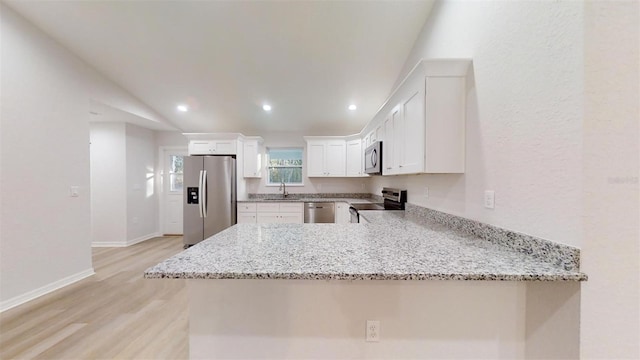 kitchen featuring light stone countertops, stainless steel appliances, kitchen peninsula, and white cabinets