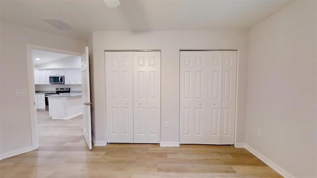 unfurnished bedroom featuring multiple closets and light hardwood / wood-style floors