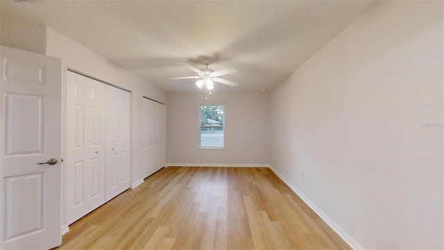 unfurnished bedroom with multiple closets, ceiling fan, and light hardwood / wood-style flooring