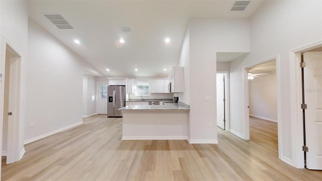 kitchen featuring white cabinetry, high vaulted ceiling, light stone counters, stainless steel fridge with ice dispenser, and kitchen peninsula