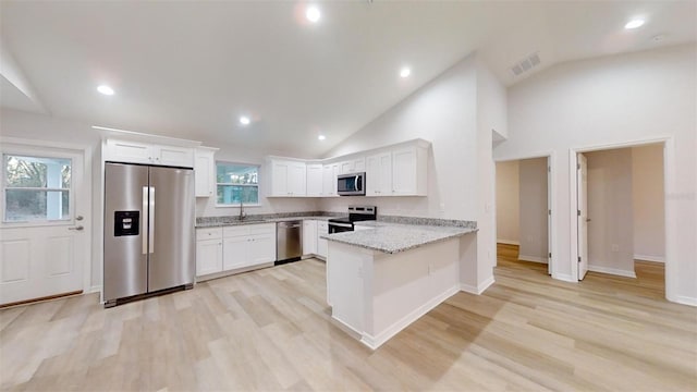 kitchen with sink, appliances with stainless steel finishes, white cabinetry, light stone counters, and kitchen peninsula