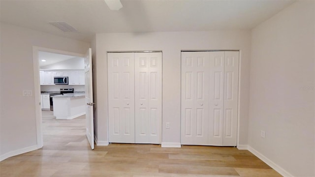 unfurnished bedroom with multiple closets, ceiling fan, and light wood-type flooring