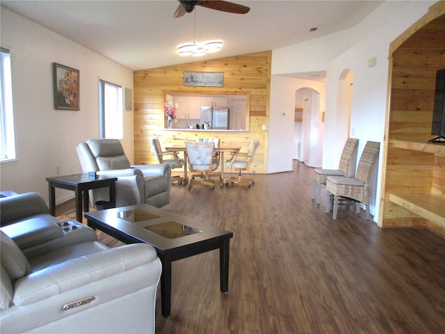 living room with wood walls, a healthy amount of sunlight, dark wood-type flooring, and lofted ceiling