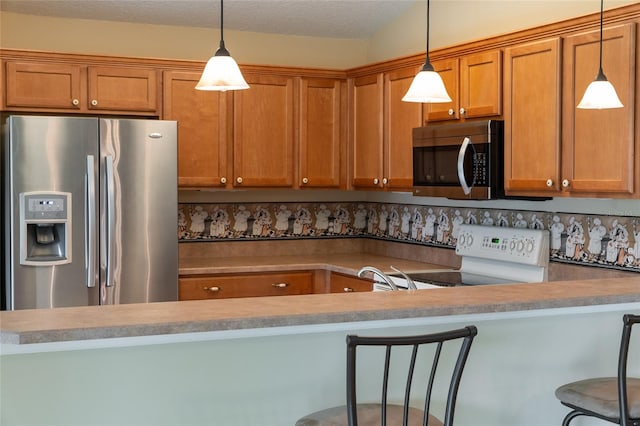 kitchen with kitchen peninsula, stainless steel appliances, a breakfast bar, decorative light fixtures, and a textured ceiling