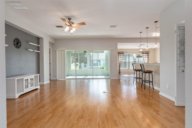 unfurnished living room featuring a textured ceiling, light wood-type flooring, and ceiling fan