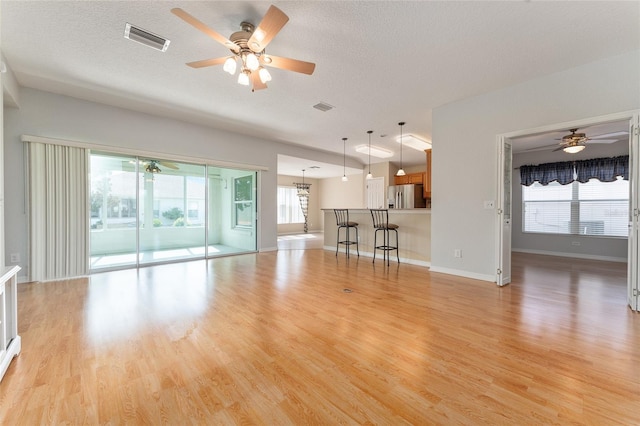 unfurnished living room featuring light hardwood / wood-style floors, a textured ceiling, plenty of natural light, and ceiling fan