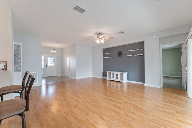 living room with ceiling fan with notable chandelier and light hardwood / wood-style floors