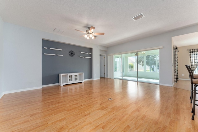 unfurnished living room featuring ceiling fan, a textured ceiling, and light hardwood / wood-style flooring