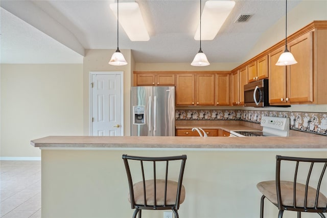 kitchen featuring light tile patterned flooring, decorative backsplash, stainless steel appliances, and a breakfast bar area