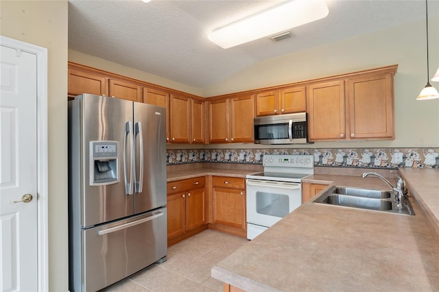 kitchen featuring sink, stainless steel appliances, lofted ceiling, pendant lighting, and light tile patterned floors