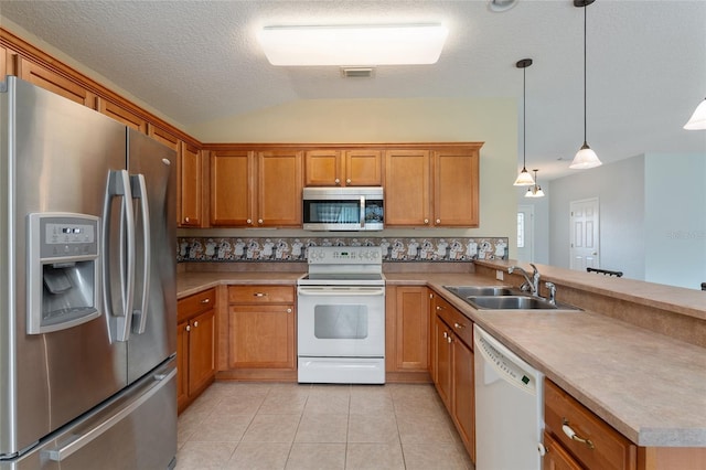 kitchen featuring lofted ceiling, kitchen peninsula, stainless steel appliances, sink, and decorative light fixtures