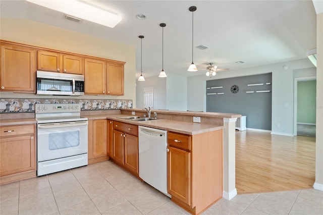 kitchen featuring kitchen peninsula, sink, light tile patterned flooring, decorative light fixtures, and white appliances