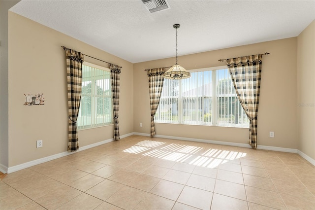 unfurnished room featuring a textured ceiling, light tile patterned floors, and plenty of natural light