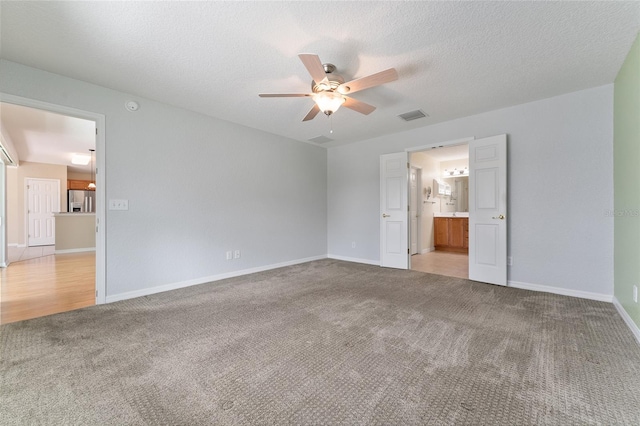 carpeted spare room with a textured ceiling and ceiling fan