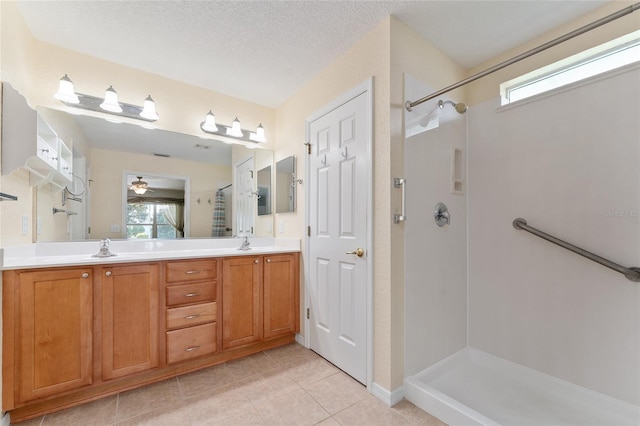 bathroom with tile patterned flooring, a shower, vanity, a textured ceiling, and ceiling fan